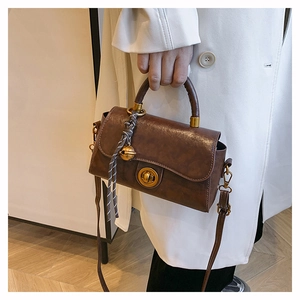 Detail of vintage crossbody bag showing glossy dark brown texture and metal twist lock