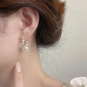 Macro shot of a minimalist silver drop earring with large white pearl and metal squares