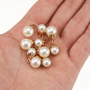 Mini pearl charms with gold petal caps held in hand for DIY jewelry making