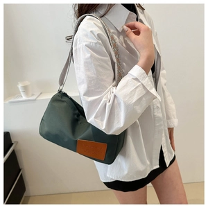 Detail of dark green nylon bag featuring a colorful woven strap and brown leather patch