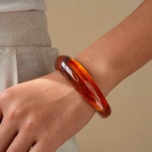 Macro shot of amber resin geometric cuff bracelet showing translucent texture and warm gloss