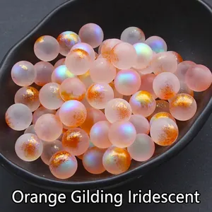 Macro shot of 12mm orange iridescent round glass beads with gold foil inside a black tray