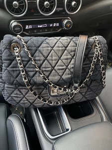 Detailed close-up of quilted denim chain bag texture and metal turn-lock closure