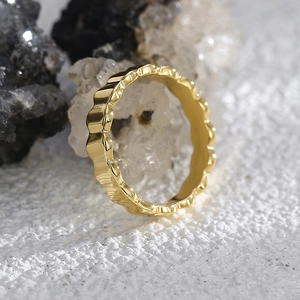 Polished 18K gold scalloped wave ring with minimalist textured design on crystal background