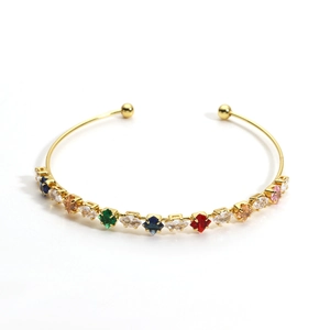 Macro view of gold plated open bangle with colorful zircon marquise and square stones