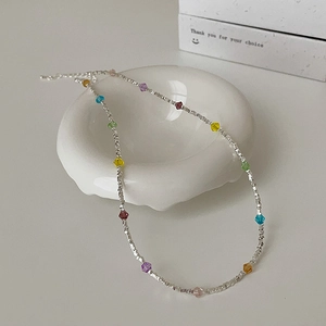 Detailed view of colorful crystal beads and silver beads on a white ceramic tray