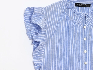 Détail de chemisier sans manches à rayures bleues et blanches avec col à volants et boutons