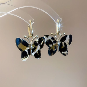 Close-up of leopard print acetate butterfly earrings with elegant gold hooks and star effect