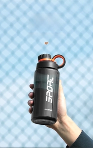 Detail of 800ml black translucent sport water bottle held outdoors with orange strap