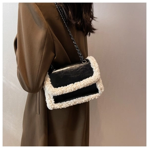 Detail of vintage black leather underarm bag with white faux fur trim and chain strap