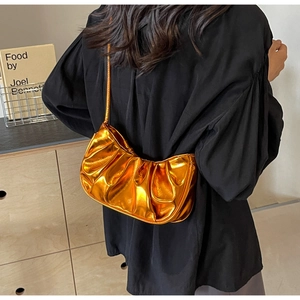 Detailed view of bright orange metallic cloud pleated shoulder bag on model back
