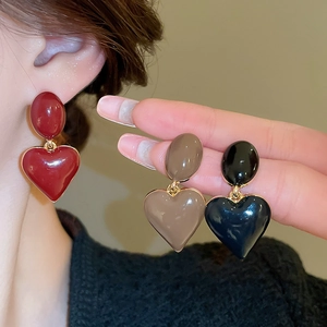 Close-up of elegant drip oil heart earrings in red, brown, and black with gold edges