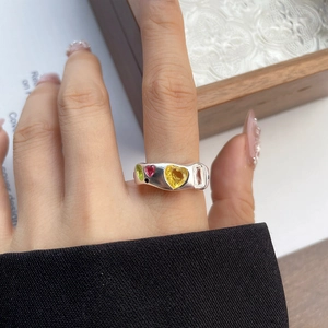 Detailed view of irregular silver ring with colorful heart stones on model finger