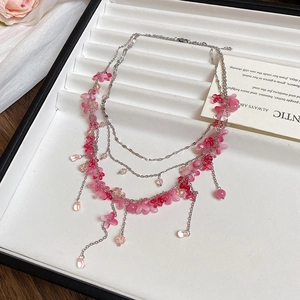 Detailed macro view of layered silver necklace with pink floral petal and bead accents