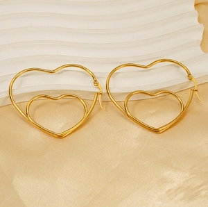 Détail de boucles d'oreilles double cœur doré sur fond satiné et texturé luxueux