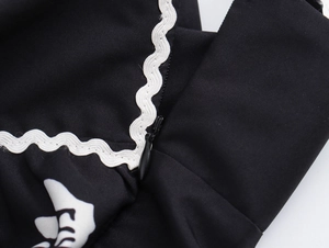 Detailaufnahme von schwarzem Kleiderstoff mit weißem Wellensaum und Reißverschluss