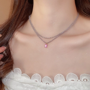 Detail view of double-layer beaded necklace featuring a pink gemstone pendant on the neck