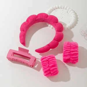 Close-up of rose pink skincare set with sponge headband, wristbands and hair claw clip