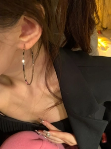 Close-up of oversized polished silver hoop earrings worn to show style and diameter
