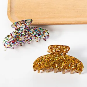 Acrylic Christmas hair claws with colorful and golden star sequins in a wooden tray