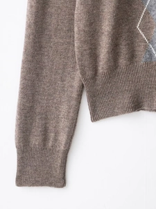 Close-up of brown argyle wool blend sweater with ribbed cuffs and textured knit fabric