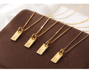 Macro view of gold rectangular alphabet pendants A-D on a premium velvet box