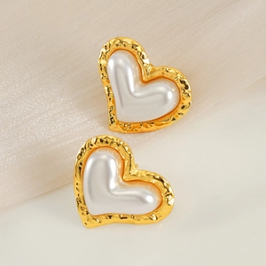 Boucles d'oreilles cœur dorées irrégulières avec perle blanche sur fond en tissu doux