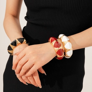 Detail of vintage wide enamel bangle set with geometric relief texture in gold and black