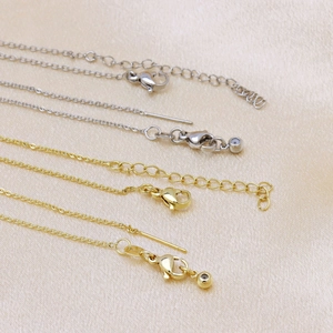 Macro detail of 18k gold and silver plated lobster clasp with extension chains on silk