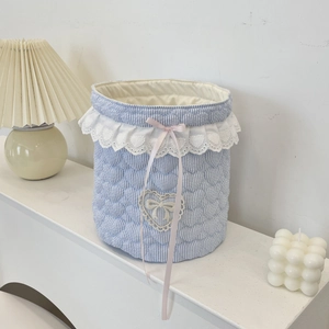 Detail of blue striped quilted storage basket with lace trim and pink silk bow