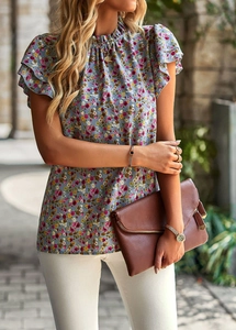Detail of floral chiffon blouse featuring elegant ruffle sleeves and high neckline texture