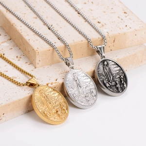 Three Fatima pendant necklaces in gold and silver on a minimalist stone display