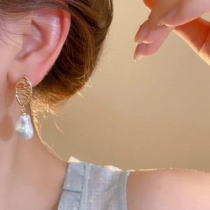 Detail view of model wearing gold-plated baroque pearl earrings in a French retro style
