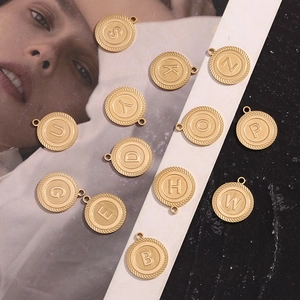 Flat lay of 18K gold plated stainless steel letter pendants with striped edge detail