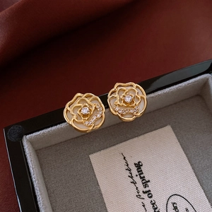 Macro detail of camellia earrings with gold base, white petals and sparkling crystals