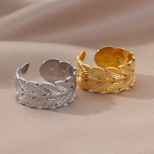 Detail shot of gold and silver feather rings with delicate leaf textures on silk