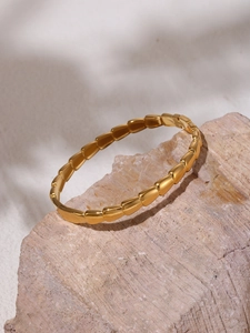 Detail of 18K gold-plated stainless steel snake-shaped bracelet on pink stone base