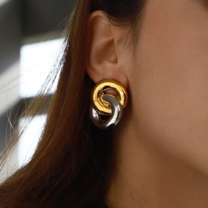 Macro shot of interlocking two-tone stainless steel earrings worn on ear