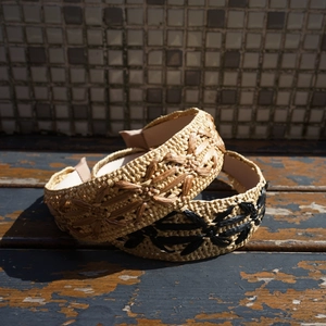 Close-up of beige and black raffia woven headbands with delicate floral pattern texture