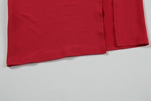 Detailed macro view of the double-stitched hem and side slit on the red knitted dress