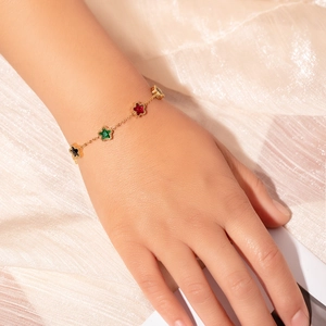Detailed close-up of a gold chain bracelet with colorful star-shaped gemstones on silk