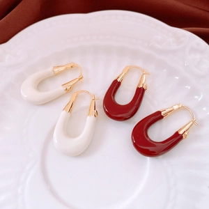French vintage gold plated U-shaped earrings in red and white enamel on a ceramic tray