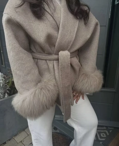 Detail of oatmeal wool coat featuring soft faux fur cuffs and a waist tie belt closure