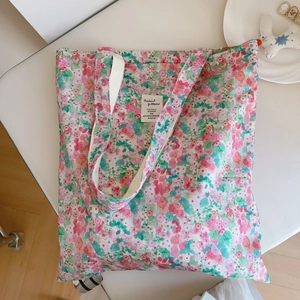 Detail of floral canvas shoulder bag featuring rose pink patterns and woven strap