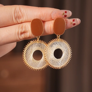 Detailed macro view of brown oval studs with gold wire-wrapped geometric hoop earrings