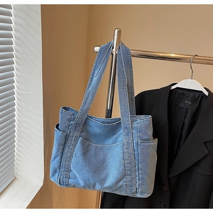Macro view showing the washed denim fabric texture and functional outer pockets on the tote bag