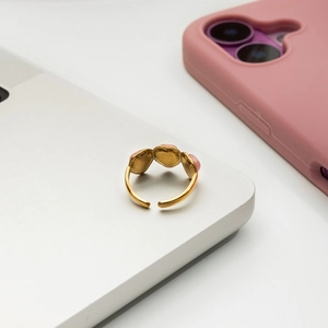 Détail d'une bague dorée réglable avec trois cœurs roses sur un ordinateur