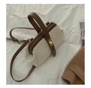 Detail view of the vintage metal clasp and leather strap on a beige and brown bag
