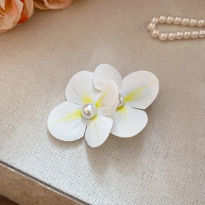 Detailed macro view of white flower hair clip with yellow center and pearl detail