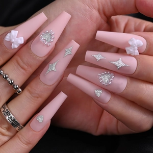 Close-up of pink long coffin nails with white bows, pearl hearts and silver glitter stars